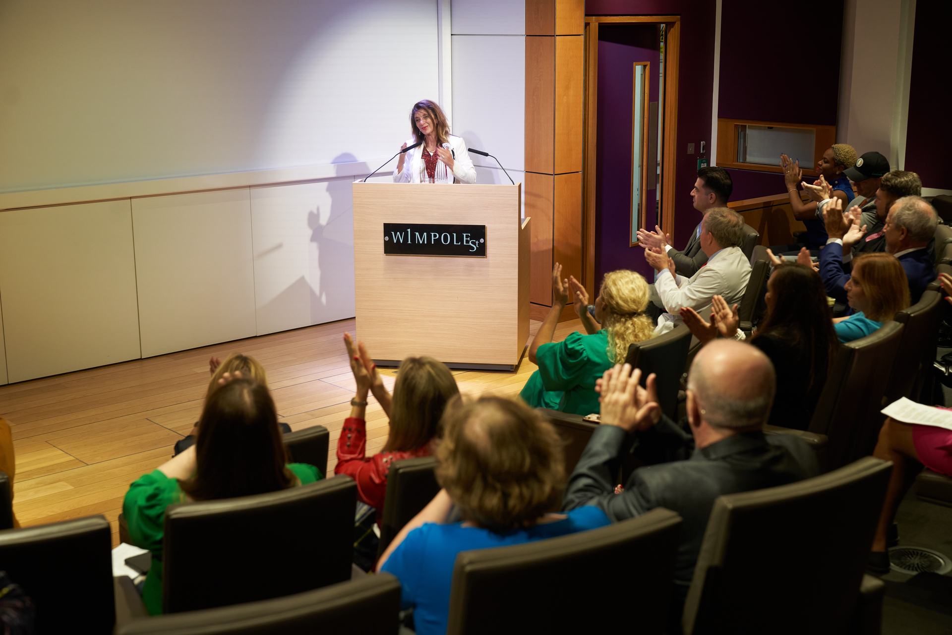 Dr. Dalal Akoury addressing an audience at Wimpole Street, London, to applause